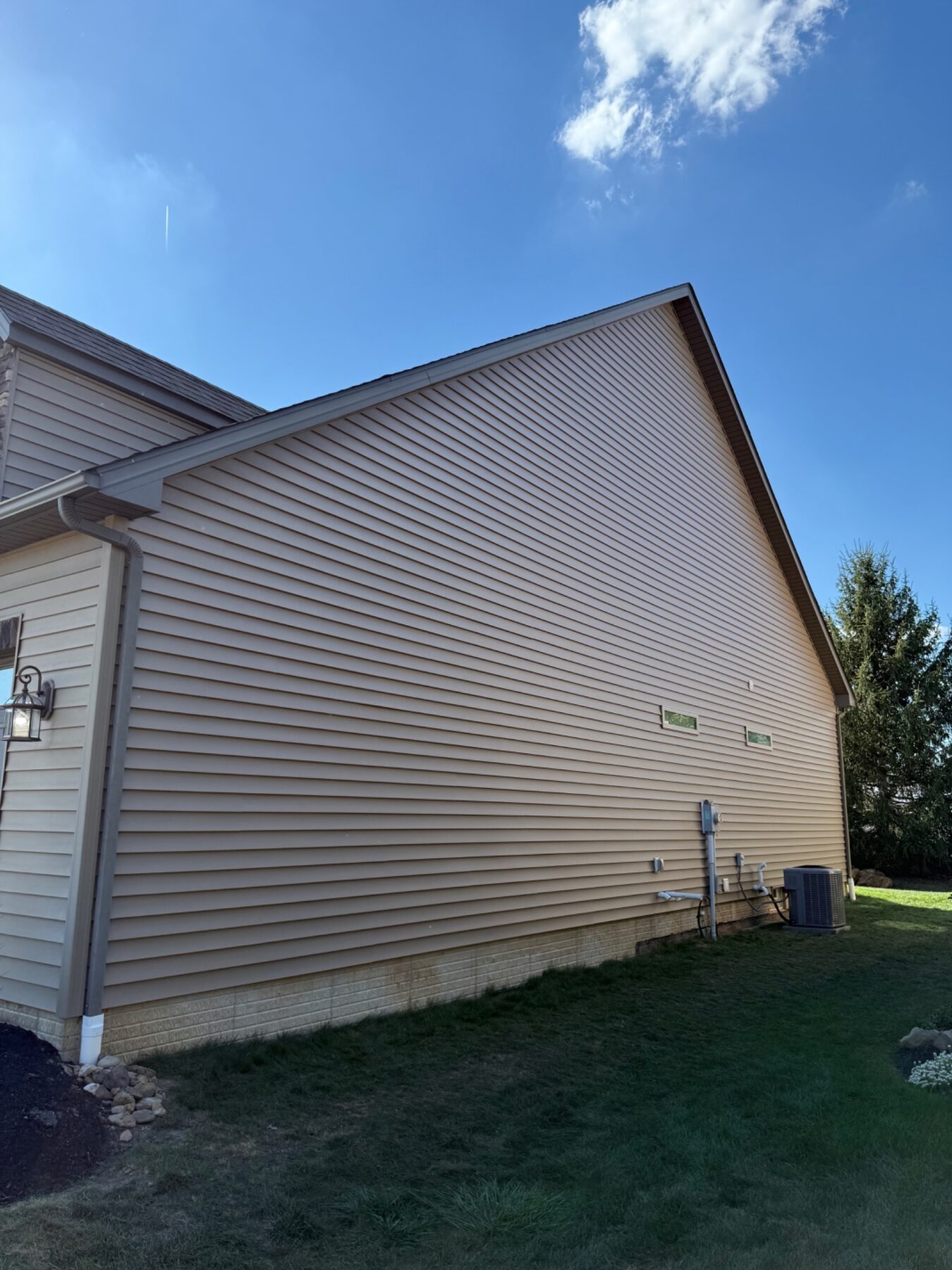 Completed beige vinyl siding on a tall residential exterior